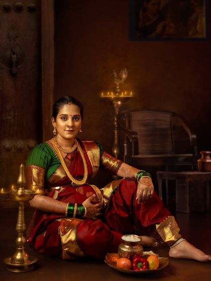 A beautiful portrait of a mom-to-be in a traditional Maharashtrian nine-yard saree, seated with offerings of fruit.