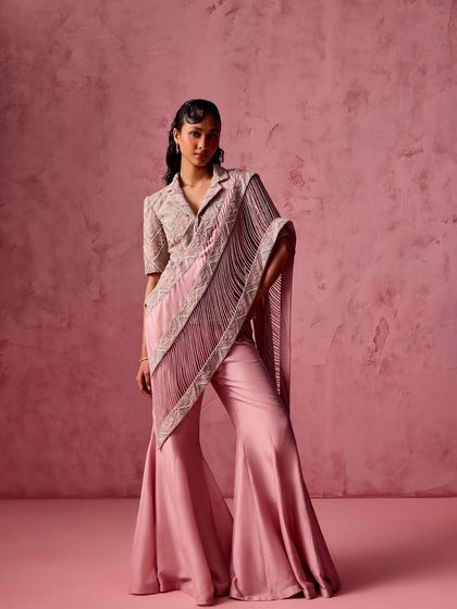 A modern take on festive wear: a collared, draped top with dramatic fringe detailing, paired with flared trousers in a beautiful rose pink.