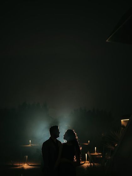 A stunning silhouette of the couple against a mysterious, foggy backdrop lit by candles. This highly atmospheric and dramatic shot is perfect for a save-the-date announcement.