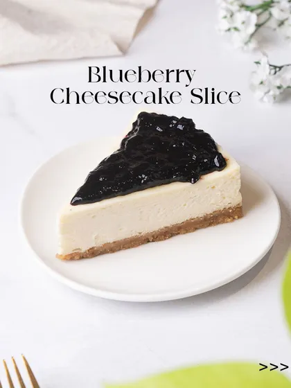 A classic Blueberry Cheesecake slice, featuring a creamy, rich filling on a crisp biscuit base, generously topped with a sweet blueberry compote. It's a bestseller for a reason.