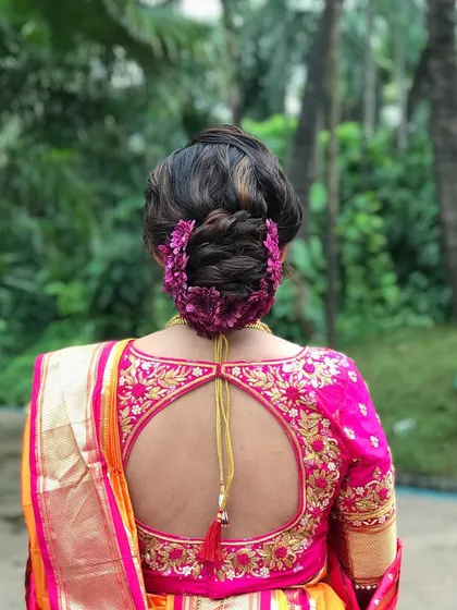 A stunning textured bun for a Maharashtrian bride, adorned with beautiful magenta flowers that match her blouse perfectly.