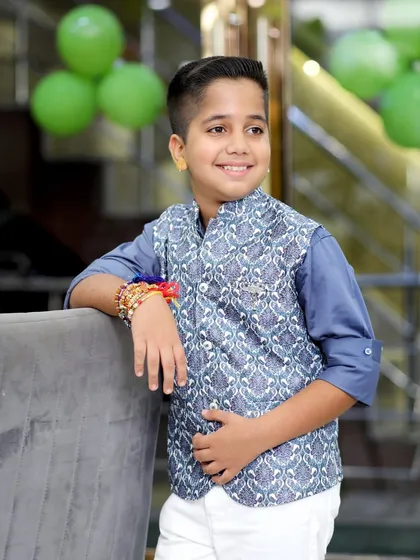 A candid, smiling portrait of the birthday boy leaning against a chair, with green balloons in the background adding to the festive atmosphere.