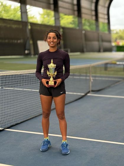 Another angle of Yashi's success, posing with her trophy near the net. Her achievements inspire everyone at the academy to keep pushing their limits.
