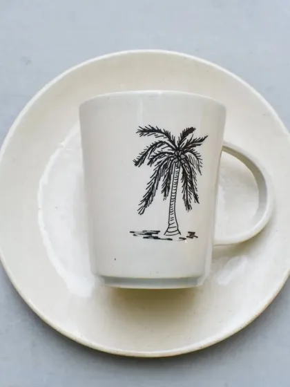 A simple, clean-lined mug with a hand-drawn palm tree illustration. This piece brings a relaxed, coastal vibe to your morning coffee.