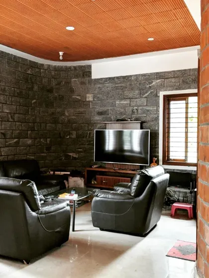A cozy TV lounge area with a curved brick wall opposite a dark stone wall, creating a den-like atmosphere.