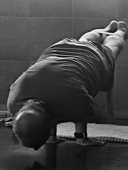 A black and white photo of Mayurasana (Peacock Pose). This advanced arm balance requires immense strength in the wrists, arms, and core.
