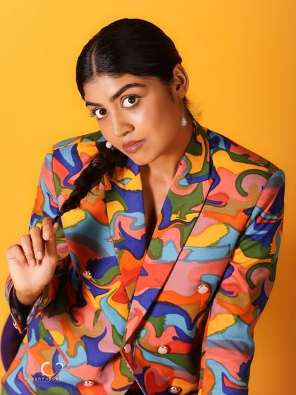 A playful and charming pose that shows off the subject's personality. The colorful suit becomes a backdrop for her expressive character.