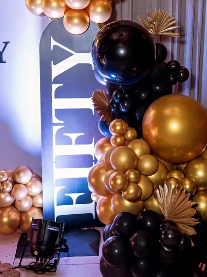 A close-up of a black and gold balloon arrangement for a 50th birthday. The combination of metallic and matte balloons adds texture and sophistication.