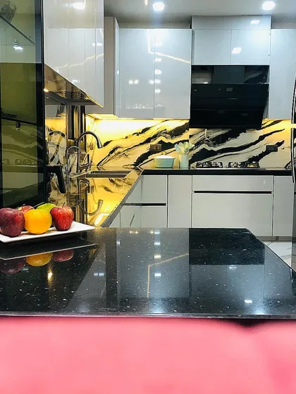 Another view of the monochromatic kitchen, showing the sleek black granite countertop and the dramatic, backlit backsplash that serves as a stunning focal point.
