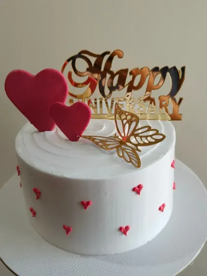 A sweet and simple anniversary cake with pink hearts and a golden butterfly. This design is also available as an eggless cake.