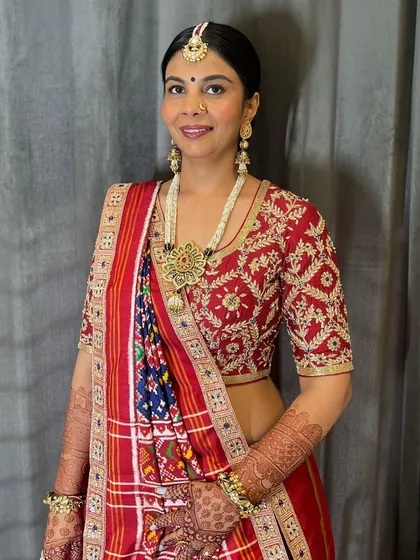 The final look of the client with her Patola saree and classic bun. This hairstyle is perfect for showcasing heavy, traditional jewelry.