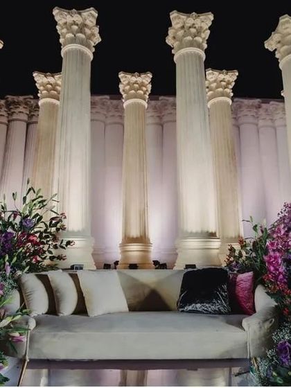 The couple's seating nestled within the overflowing floral arrangements, perfectly framed by the majestic Roman pillars. This design creates a sense of both intimacy and grandeur.