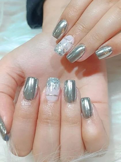 A striking manicure featuring a metallic silver chrome finish on square nails, with a delicate glitter accent nail.