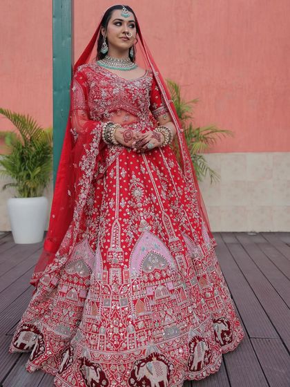 The bride adjusting her dupatta, giving a full view of the stunning red lehenga. The elephant motifs on the border are a unique and auspicious detail.