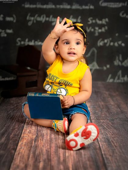 Waving to the camera, this little scholar is happy to be in her "class." A playful and engaging portrait.