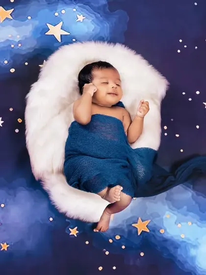 A dreamy celestial theme, with a baby sleeping on a soft white moon under a starry night sky.