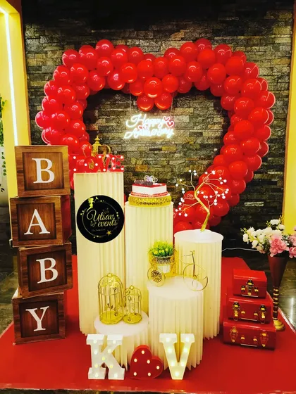 A beautiful anniversary decoration with a red balloon heart, 'BABY' blocks, and a neon 'Happy Birthday' sign, perfect for celebrating love.