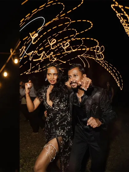 A candid shot of the couple dancing, with light trails from the string lights creating a fun, energetic vibe.