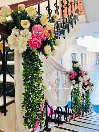 Staircase decoration for an engagement ceremony. I use floral arrangements and flowing drapes to beautify every part of the venue, ensuring a festive feel throughout.