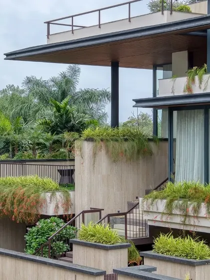 The interplay of concrete planters, steel railings, and lush vegetation gives the facade a rich, textural quality.