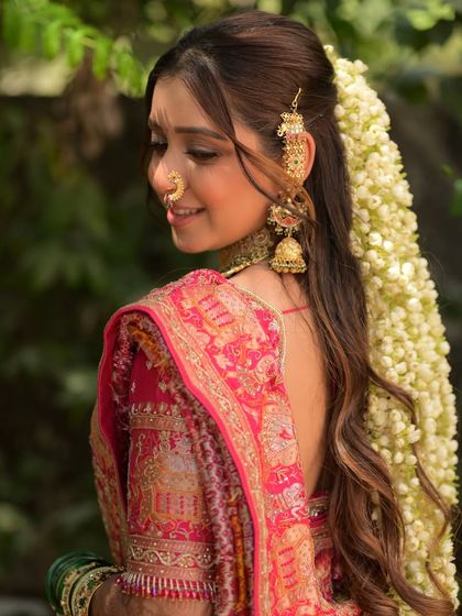 A closer view of the half-up hairstyle with a cascade of fresh flowers. The makeup is kept soft and glowing to complement this romantic and traditional bridal element.