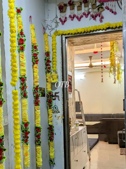 Decorating the entrance to a home with vertical strings of artificial marigold and red flowers. This is a lovely way to welcome guests for any festive occasion.