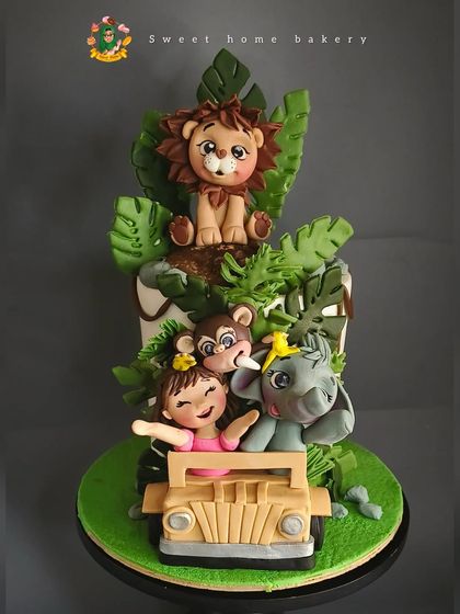 Welcome to the jungle! This safari-themed cake was made for Falyn's second birthday. It features a little girl on a jeep adventure with her friendly lion, monkey, and elephant pals, all handcrafted from fondant and surrounded by lush, edible leaves.