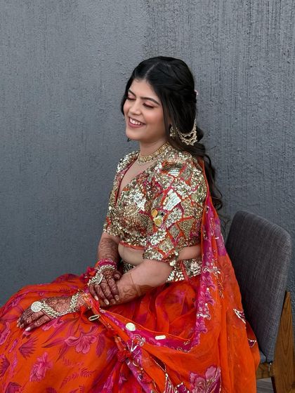 A seated portrait of the bride in her colorful, sequined outfit. The makeup is fun and glamorous, matching the energy of the event.