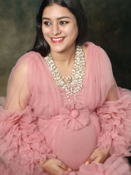 A beautiful close-up of a smiling mom-to-be in a frilly pink gown. Her happy expression and the soft texture of the dress create a joyful and feminine portrait.