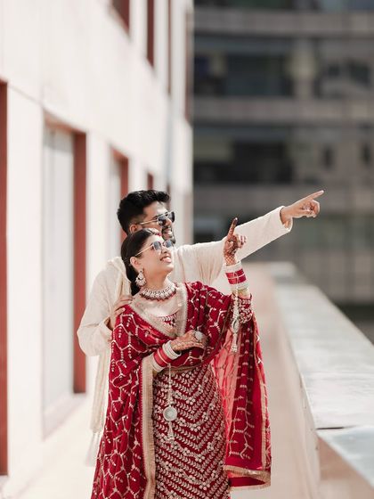 A sweet, candid moment from what looks like a post-Haldi or Chura ceremony. The couple is looking towards the future, with the bride pointing at something in the distance, symbolizing the start of their new journey.