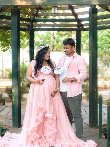 A fun gender reveal moment for this couple. They hold up signs saying "I vote Girl" and "I vote Boy" during their outdoor shoot in a gazebo.