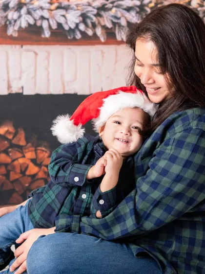 Cozy flannel shirts and a happy baby make for a perfect Christmas photo. The fireplace backdrop adds a warm, rustic feel to the holiday portraits.