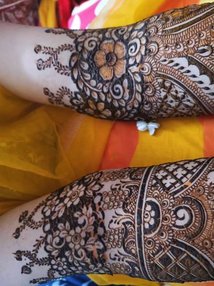 A close-up of the detailed work on the back of the hands for bride Aqsa. The floral and paisley patterns are classic choices for bridal mehendi.
