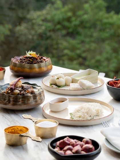 A full spread of Kodava delicacies, including steamed rice dumplings (kadambuttu), pandi curry, and various chutneys. This feast showcases the diversity and richness of Coorg's cuisine.