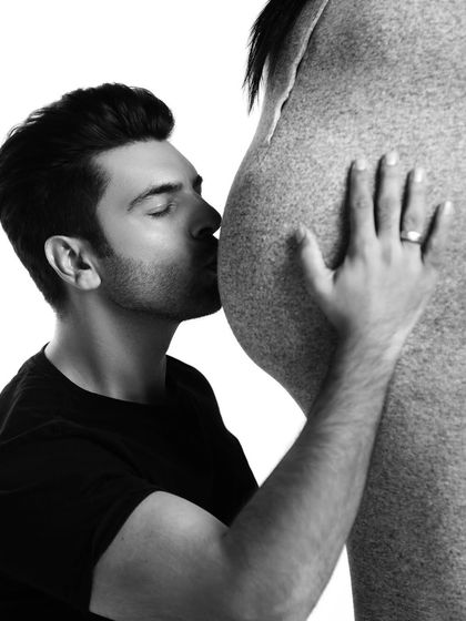 A close-up, artistic shot of a father-to-be's love. This black and white image beautifully captures the tenderness and connection to the baby bump.