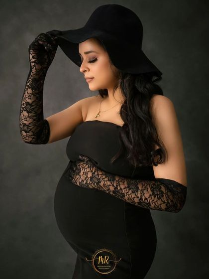 A classic and elegant close-up. This portrait in a black dress, hat, and lace gloves has a vintage feel, focusing on the mother's serene expression.