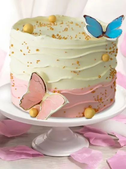 A whimsical butterfly cake with a pink and white ombre effect. The edible butterflies and gold sprinkles add a touch of magic and elegance.