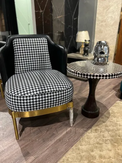 A pair of armchairs that make a graphic statement with a black-and-white houndstooth fabric. Paired with a black leather back and a gold-finished base, they are the definition of modern chic.