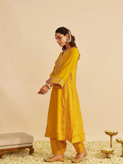 A side profile of the mustard yellow kurta set, showing its graceful A-line silhouette and patterned salwar.