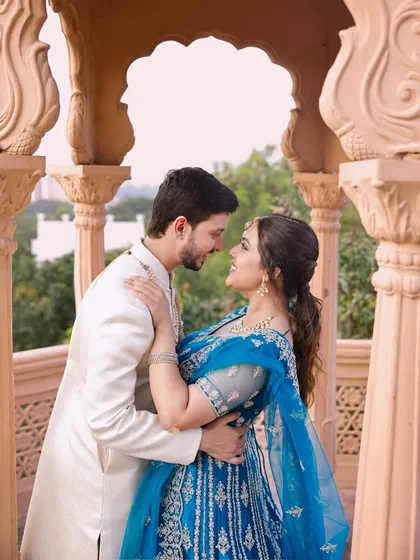 An intimate moment captured during a pre-wedding shoot. The couple's coordinated outfits, a blue lehenga and an ivory sherwani, were chosen to create a visually harmonious portrait that feels both grand and personal.