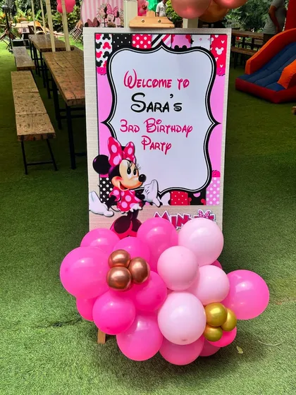 The personalized welcome sign for the outdoor Minnie Mouse party, surrounded by lush greenery.