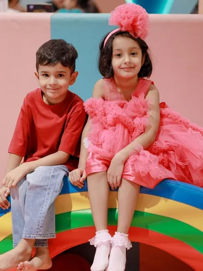 A birthday girl and her friend sitting on our rainbow climber during a magical unicorn party.