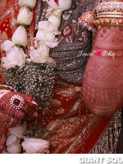 A close-up of the bride's hands during a wedding ritual, adorned with a large red stone ring and traditional bangles.