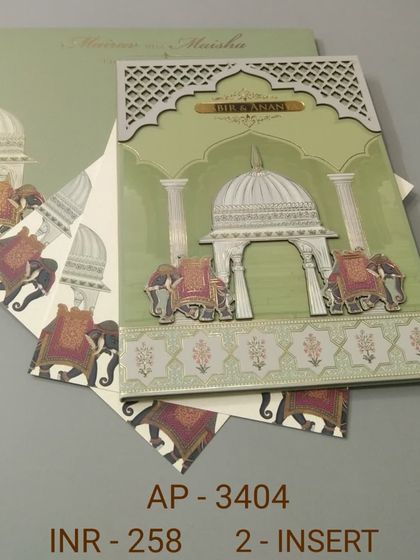 This sage green invitation showcases a grand palace dome flanked by decorated elephants, all with raised printing and silver foil. The matching inserts continue the elephant motif for a coordinated wedding stationery suite.