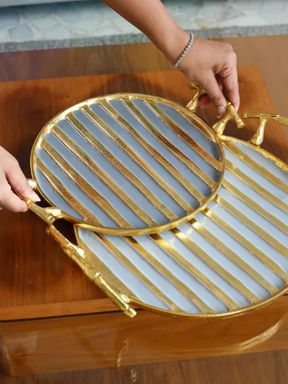 A pair of our round trays with a striking grey and gold stripe pattern and branch-like handles. These modern and artistic trays are designed to make a statement.