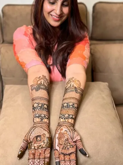 A beautiful portrait of a bride showing off her full bridal mehndi, which includes custom portraits on her palms. My goal is to make every bride feel this happy and beautiful.
