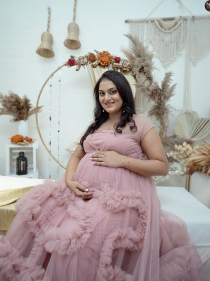 A smiling portrait of the mother-to-be, surrounded by the soft textures of the boho-chic studio set. This setup is designed to be comfortable, allowing for natural and happy expressions.