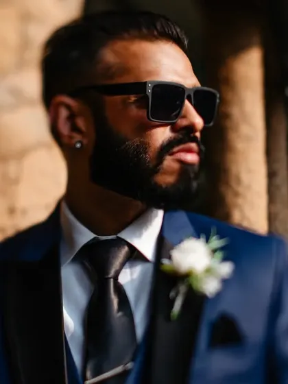 A portrait that plays with focus and depth. The groom is sharp in the foreground while the bride is softly blurred in the background, creating a layered composition with a cool, modern feel.