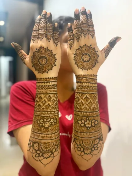 A client happily showing off her full-arm Ganesh Chaturthi mehndi, complete with lotus mandalas.