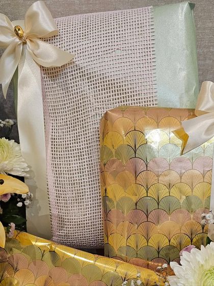 A close-up of the custom gift wrap used in a pastel trousseau. The iridescent fan pattern and the textured mesh wrap add layers of detail and sophistication to the overall presentation.